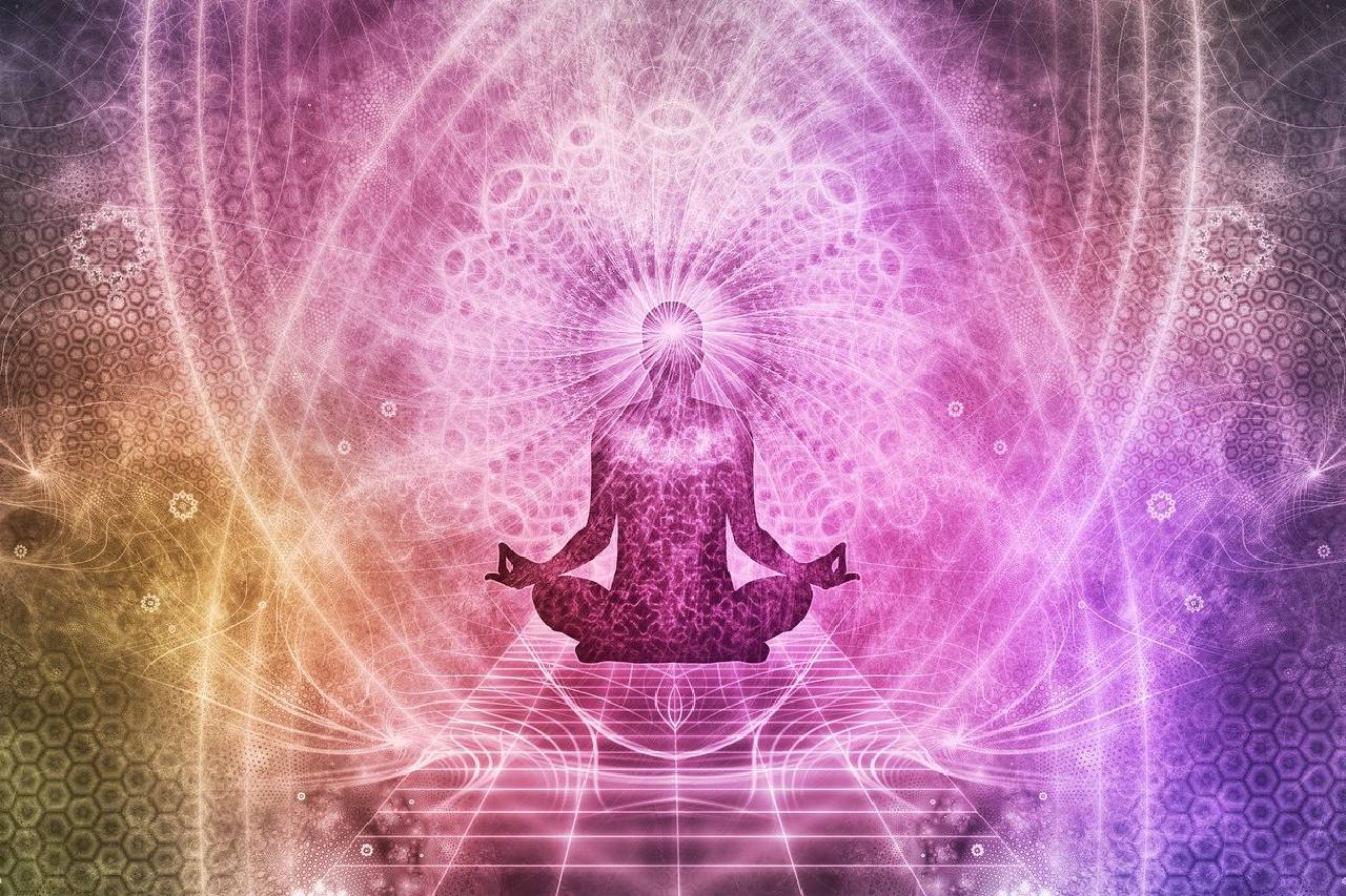A person sitting in the lotus position with their hands in the air.